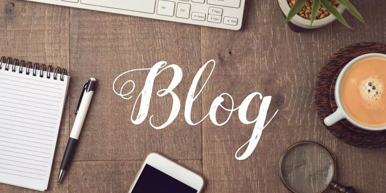 Schreibtisch mit Notizblock, Laptop, Smartphone, Lupe und Kaffee