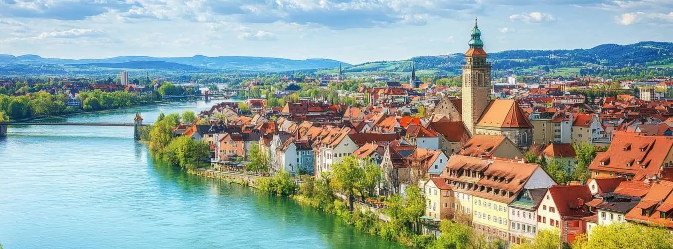 Blick auf Cham in Bayern mit historischen Gebäuden am Fluss und üppigem Grün unter strahlend blauem Himmel. Luftaufnahme der Stadt Cham.
