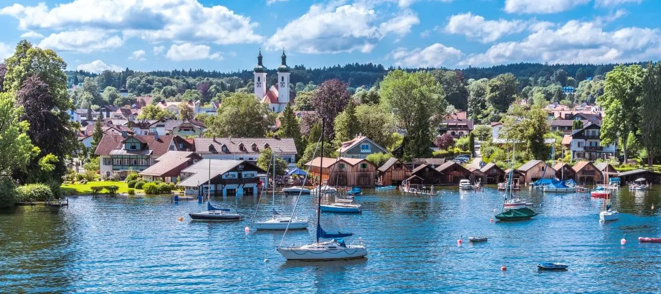 Tutzing am Starnberger See unter weiß-blauem Himmel und Segelyachten in der Bucht