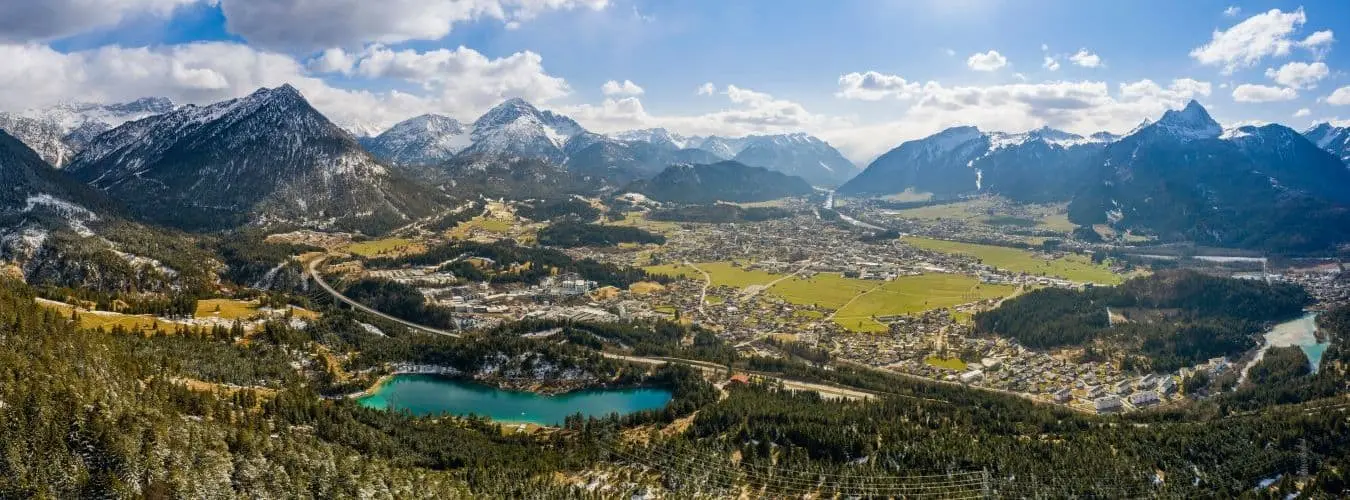 Panorama des kreisrunden, tiefen Talbeckens von Reutte und Breitenwang mit dem Urisee-See an einem sonnigen Frühlingstag