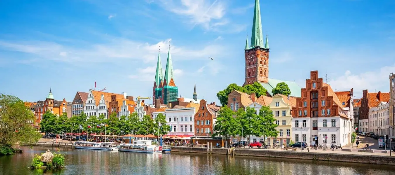 Klassischer Panoramablick auf die historische Skyline der Hansestadt Lübeck mit der berühmten Marienkirche an einem wunderschönen sonnigen Sommertag mit blauem Himmel