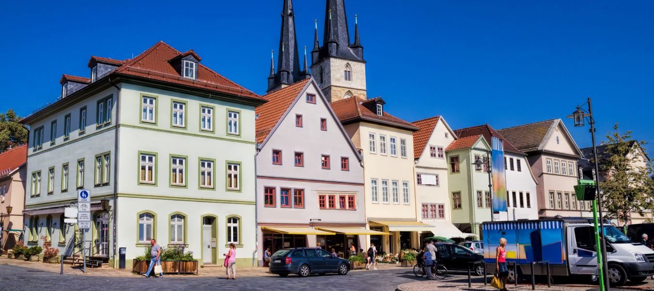 Blick auf bunte Saalfelder Altbauten mit Johanneskirche im Hintergrund bei blauem Himmel