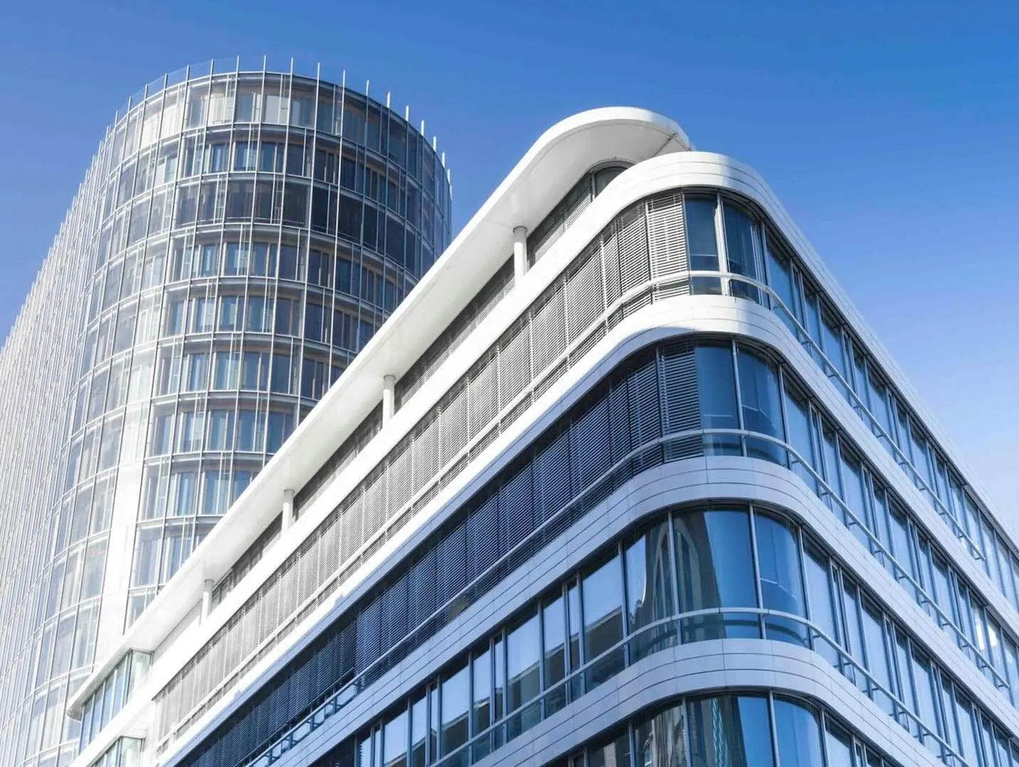 Gewerbeimmobilie: geschwungene Glasfassade eines modernen Bürogebäudes im Sonnenlicht