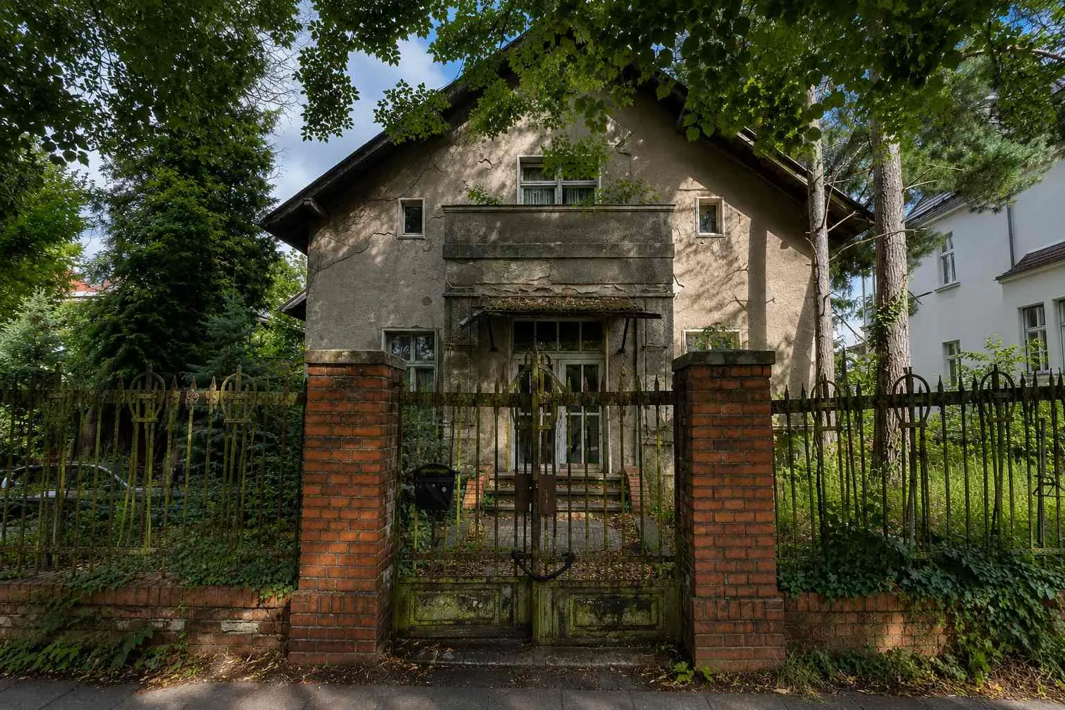 Leer stehendes Einfamilienhaus mit geschlossenem Gartentor – Symbolbild für die Risiken eines längeren Immobilienleerstands.