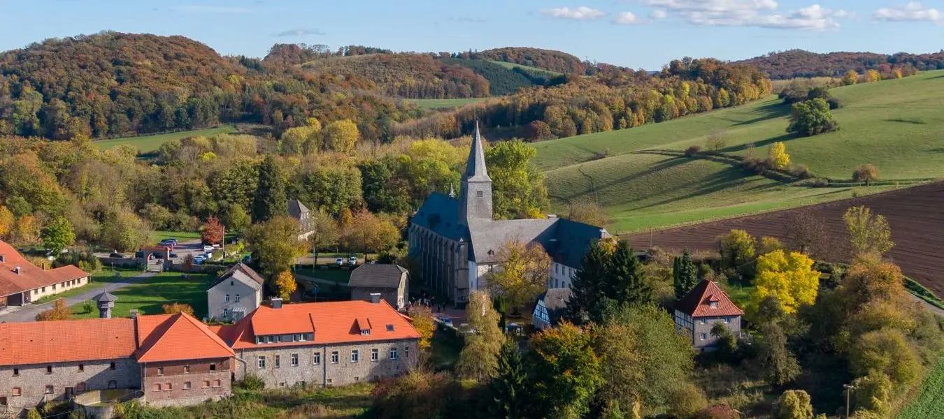 Die Klosterkirche Oelinghausen inmitten einer herbstlichen Landschaft