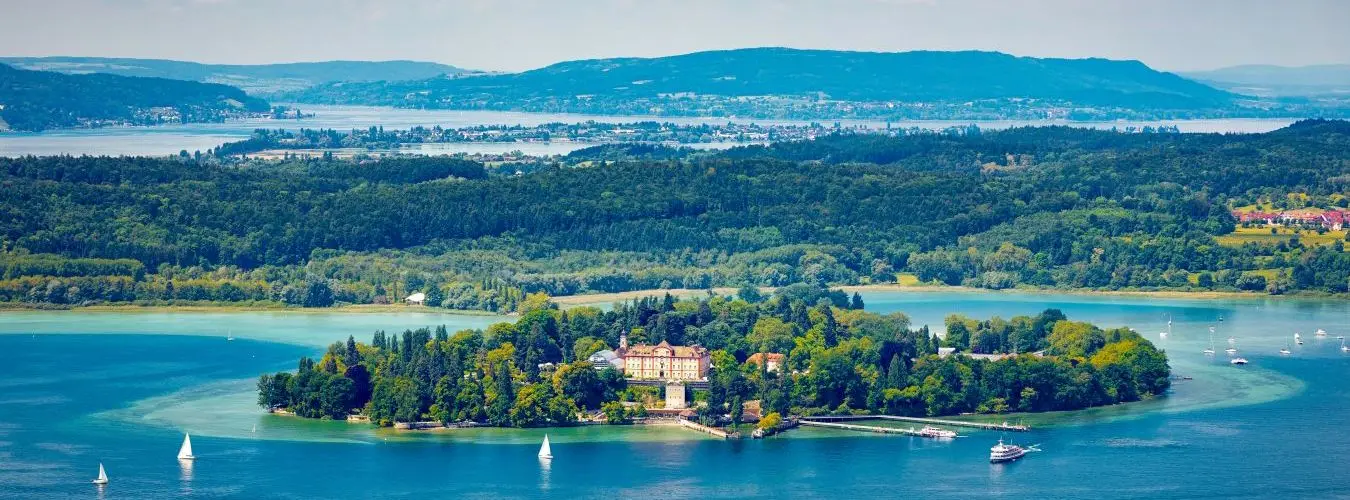Luftaufnahme der Insel Mainau im Bodensee mit Schloss, Segelbooten und bewaldetem Ufer