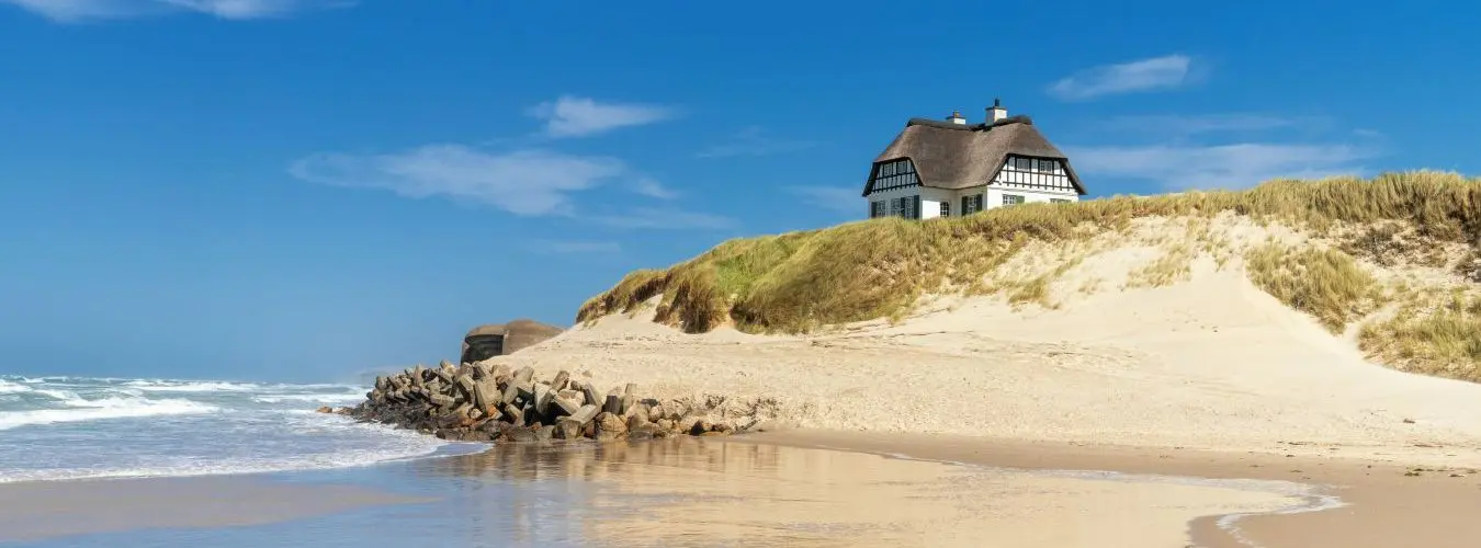 Haus mit Reetdach auf einem Hügel in den Dünen an der Nordseeküste