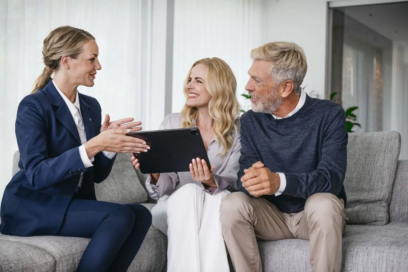Maklerin im Gespräch mit Eigentümern auf einer Couch