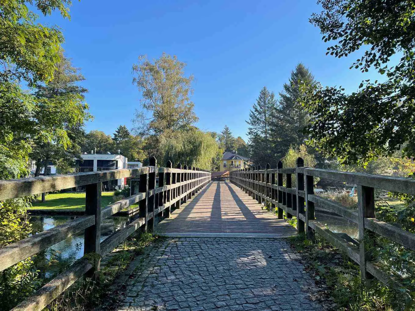 Blick über die historische Russenbrücke nach Hessenwinkel mit Wasser, Bäumen und Villen am Ufer des Alten Spreearms.