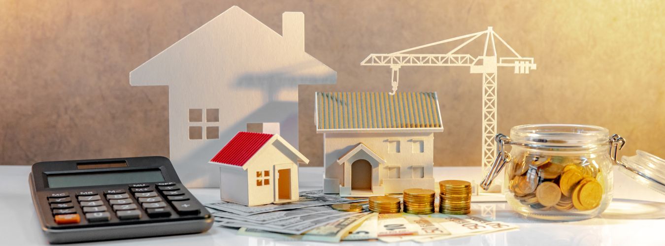 Ingatlanfejlesztés. Érmék halmaza nemzetközi bankjegyeken zsebszámológéppel, ház és daru modellekkel
