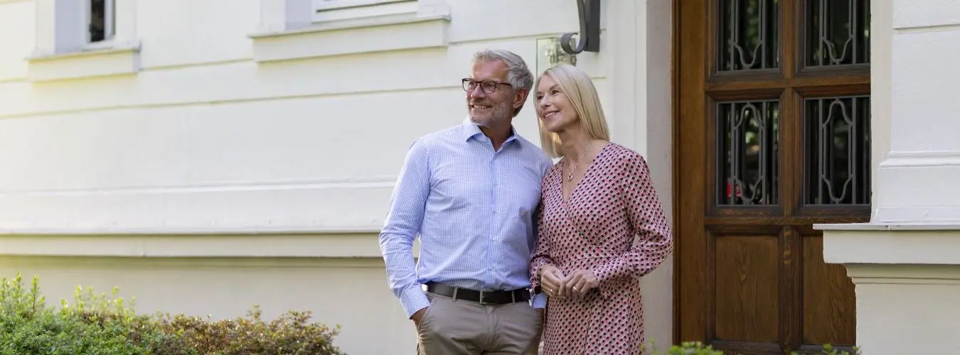 Couple âgé à l'air heureux devant un bien immobilier