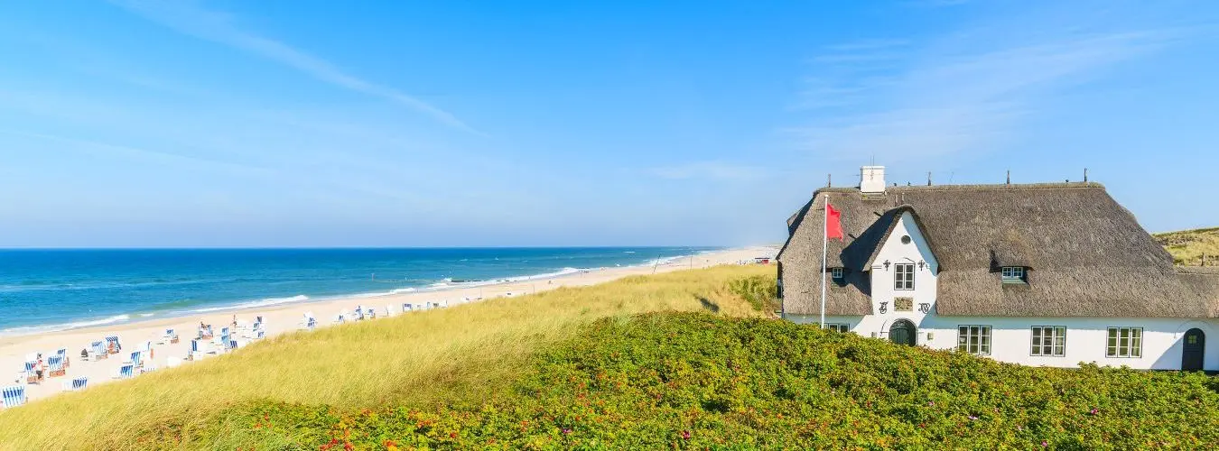 Typisches friesisches Haus mit Strohdach auf einer Klippe am Strand von Kampen